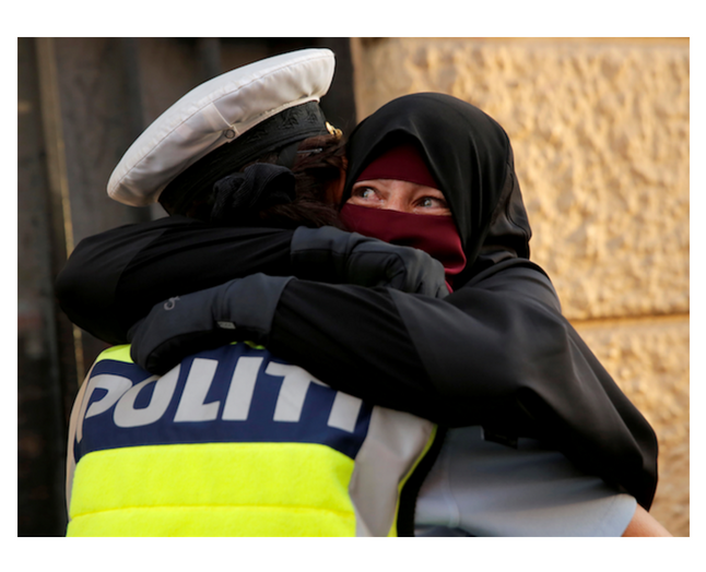 En kvindelig betjent krammer en niqab-klædt kvinde under en demonstration mod tildækningsforbuddet. Siger kropssproget egentlig ikke mere i denne situation, end tøjet gør? Foto: Ritzau Scanpix