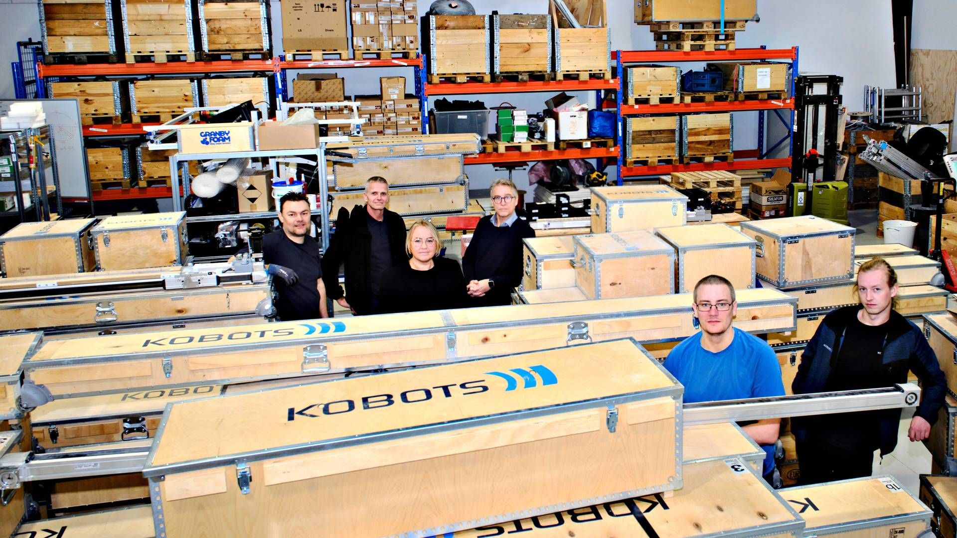 Seks ud af Kobots 10 nuværende medarbejdere samlet sammen med et hav af robotter, som var på vej til USA. | Foto: Magnus Møller