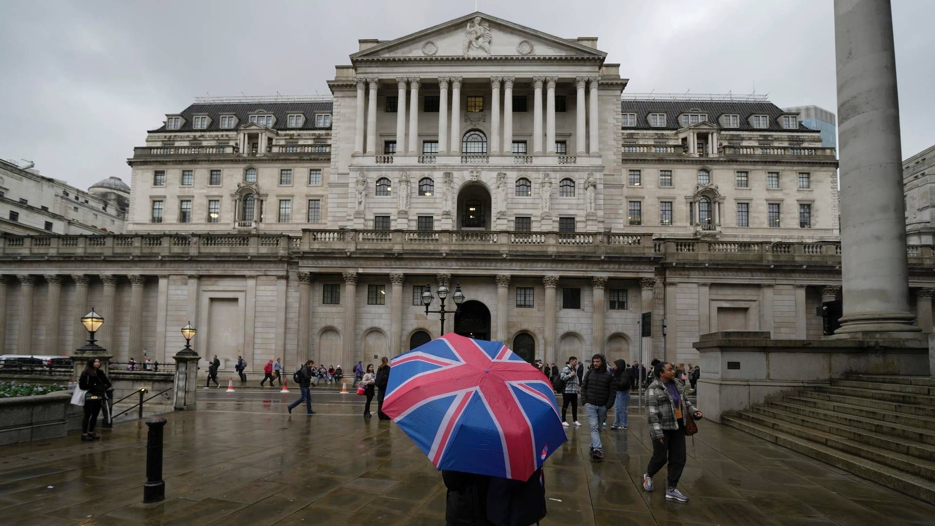 En kvinne med en paraply står foran Bank of England, i finansdistriktet i London. | Foto: Kin Cheung / AP