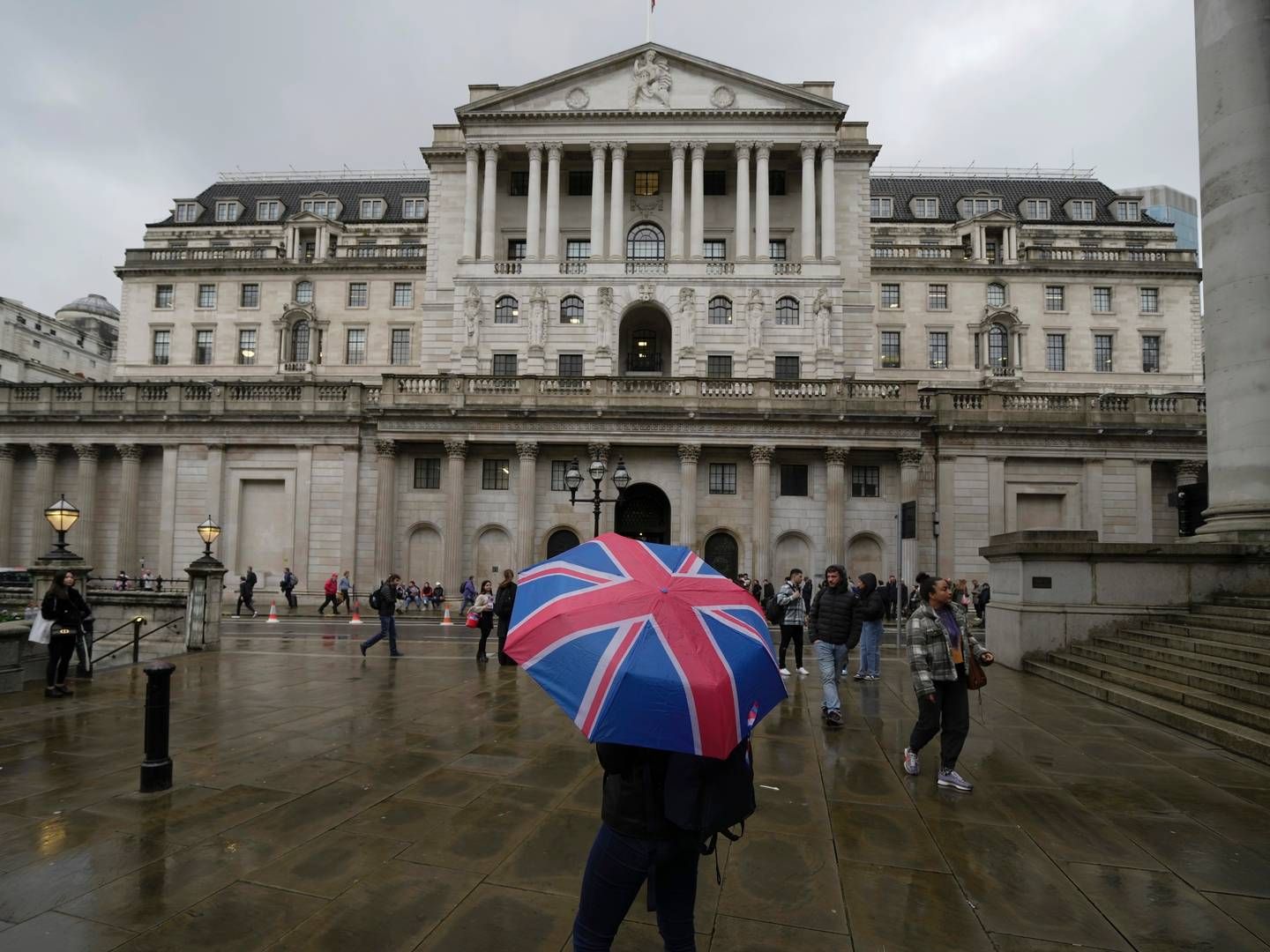 En kvinne med en paraply står foran Bank of England, i finansdistriktet i London. | Foto: Kin Cheung / AP