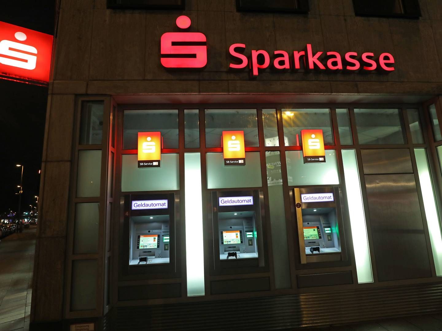 Beleuchtete Geldautomaten an der Fassade einer Sparkasse | Photo: picture alliance/dpa | Oliver Berg
