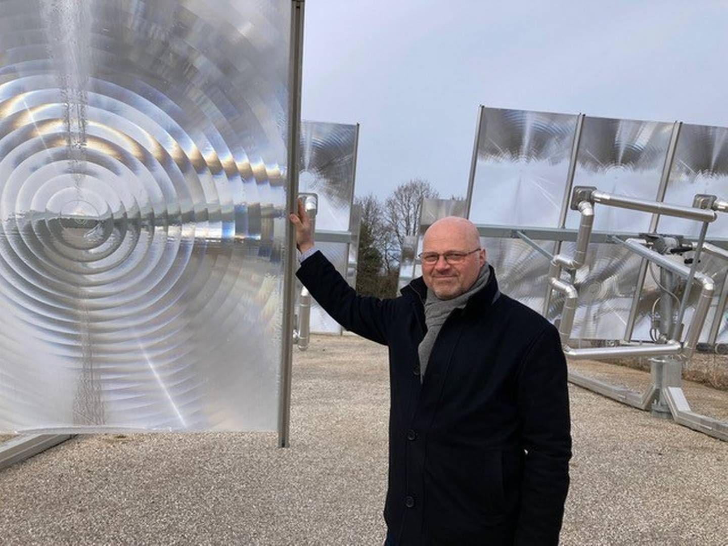 COO Lars Wiggers på Heliacs højtemperatur solfanger-anlæg i Hørsholm. Man kan tydeligt se, at overfladen på panelerne har en belægning med et særligt mønster., der samler lyset i ét punkt. | Foto: Sanne Wittrup