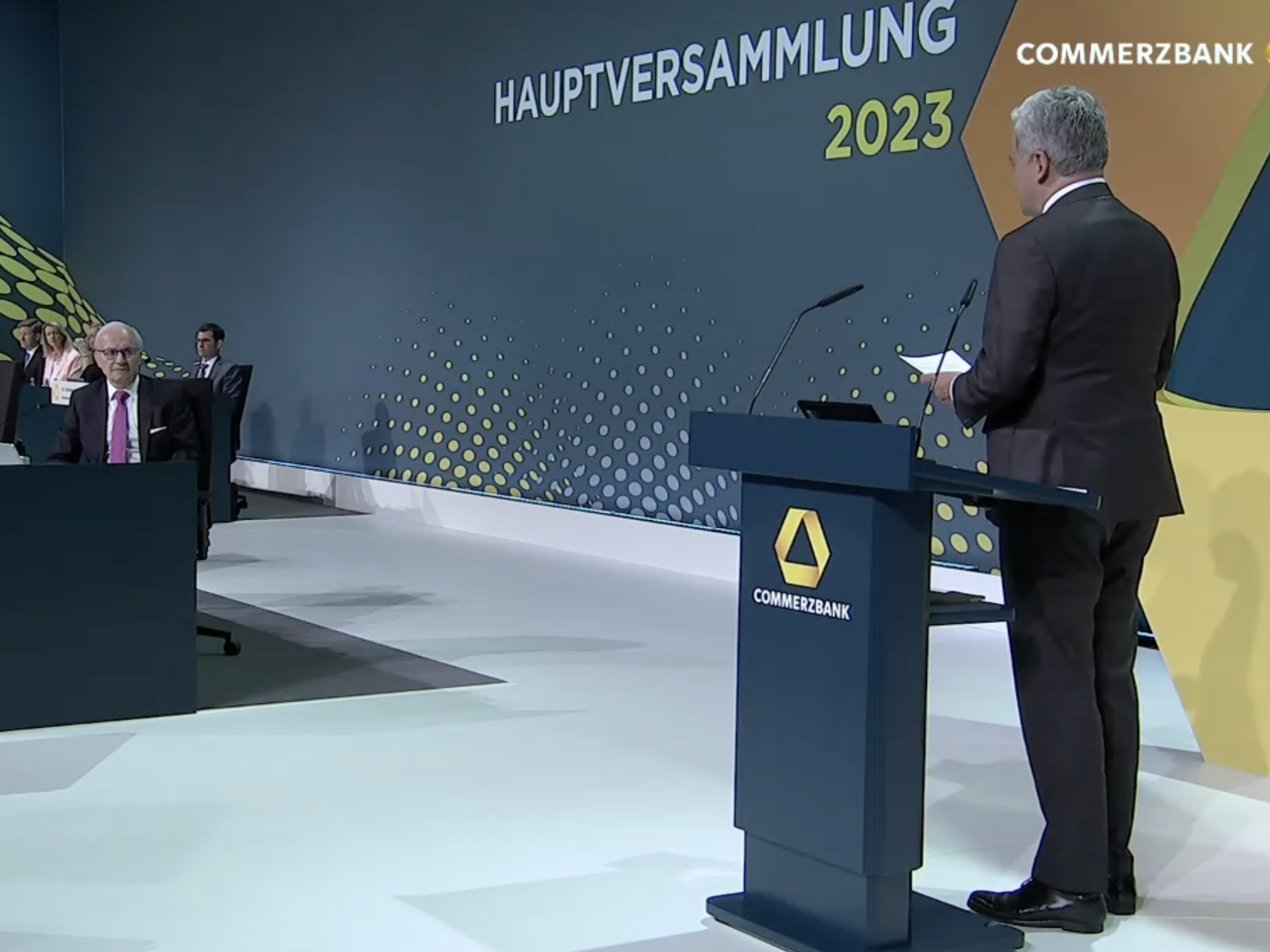 Commerzbankchef Manfred Knof wendet sich in seiner Rede direkt an den scheidenden Aufsichtsratschef Helmut Gottschalk. | Foto: Screenshot: FinanzBusiness