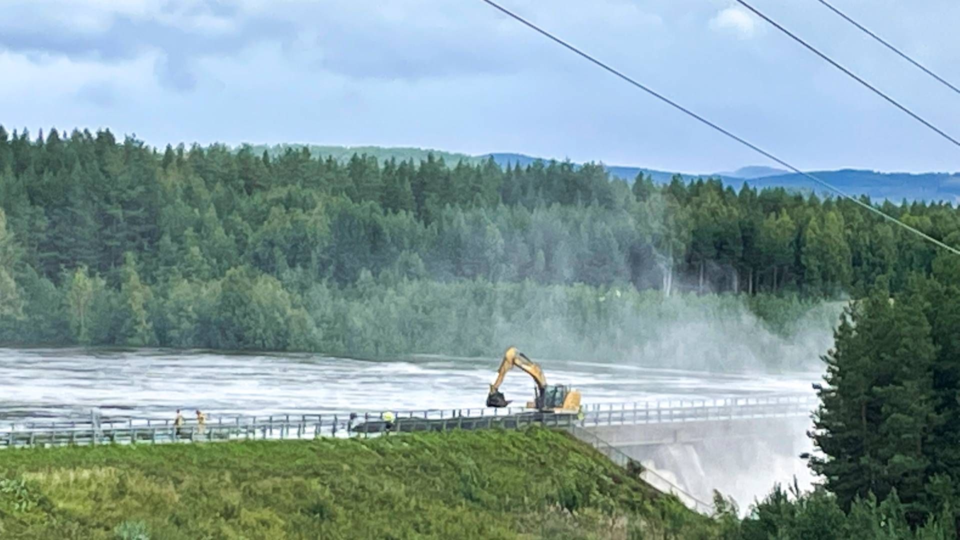 Demningen i Braskereidfoss i Våler der en demning kan bli sprengt etter at vannet ikke kommer seg forbi slusene. Mannskaper driver nå å bygger på demningen slik at den skal kunne ta imot høyere vannstand. | Foto: Bård Langvandslien / NTB