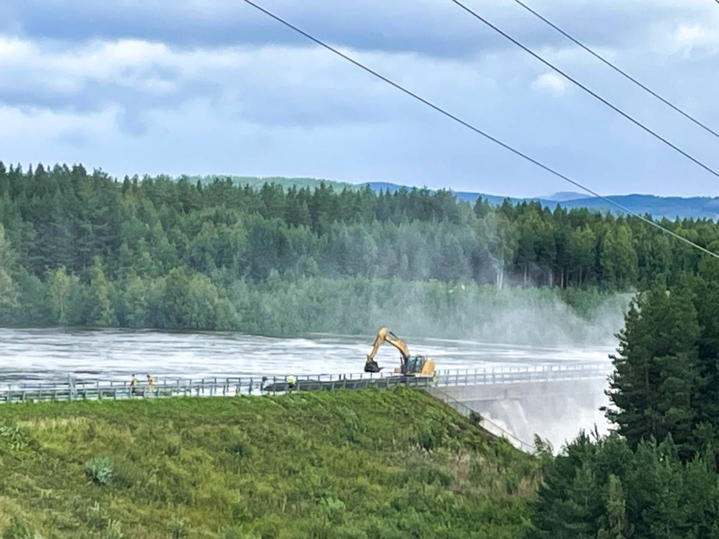 Demningen i Braskereidfoss i Våler der en demning kan bli sprengt etter at vannet ikke kommer seg forbi slusene. Mannskaper driver nå å bygger på demningen slik at den skal kunne ta imot høyere vannstand. | Foto: Bård Langvandslien / NTB