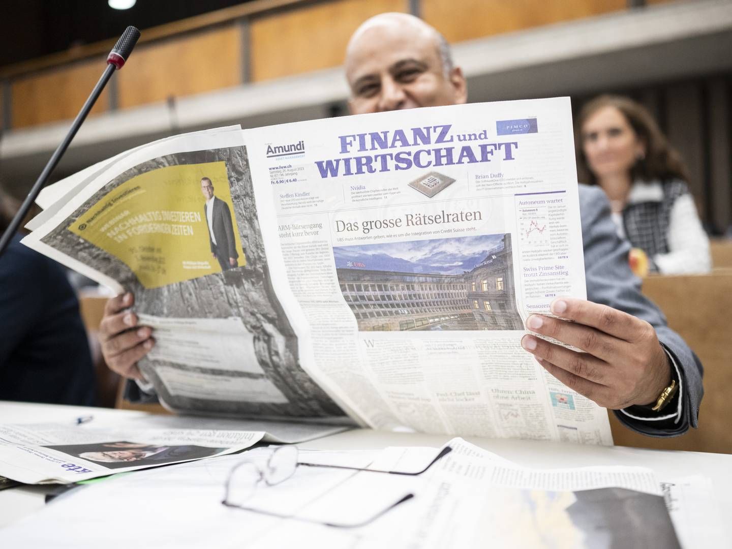 Nationalrat Jean-Philippe Pinto (Die Mitte) liest die Zeitung "Finanz und Wirtschaft", auf dessen Titelseite ein Bild der UBS prangt. | Photo: picture alliance/KEYSTONE | ENNIO LEANZA