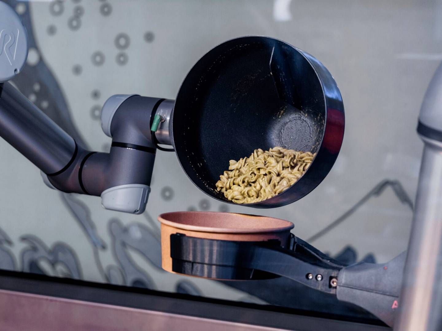 En robot i gang med at hælde færdiglavet mad i en skål. Arkivfoto: Markus Scholz/AP/Ritzau Scanpix