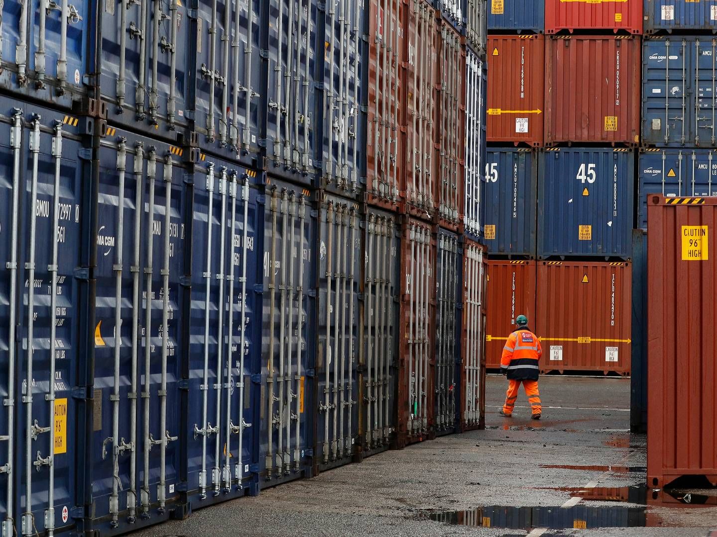En havnearbejder går forbi tårne af containere på havnen i Liverpool. Mængden af containere i havnene i Storbritannien er faldet 12 pct. i første halvår af 2023. | Foto: Phil Noble/Reuters/Ritzau Scanpix