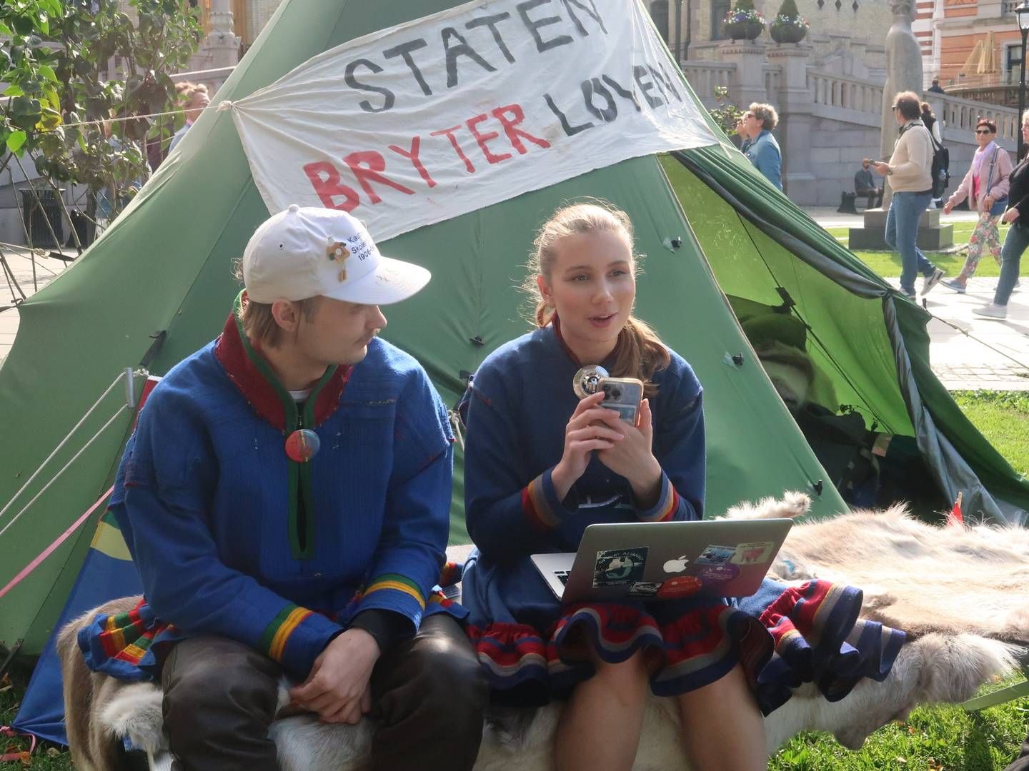 «STATEN BRYTER LOVEN» står det på en lavvu utenfor Stortinget. Her har Mihkkal Hætta (til venstre) sagt han skal bo i protest frem til Fosen-dommen blir fulgt opp. Ella Marie Hætta Isaksen (til høyre) har delt Jusstudentenes Fosenopprop i sosiale medier. | Foto: Linda Sandvik