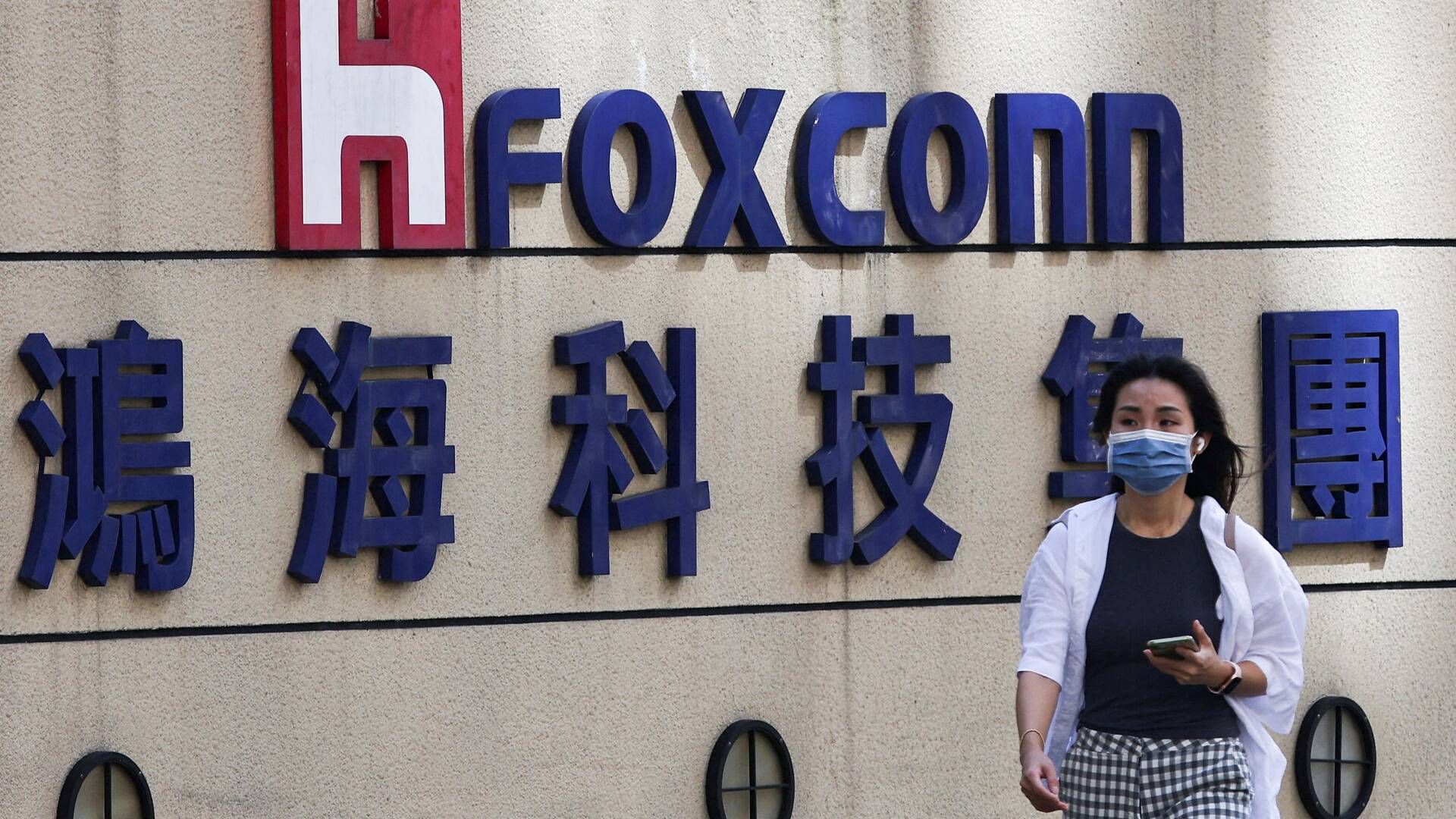 En kvinde går forbi Foxconns logo uden for virksomhedens bygning i Taipei. | Foto: Ann Wang/Reuters/Ritzau Scanpix