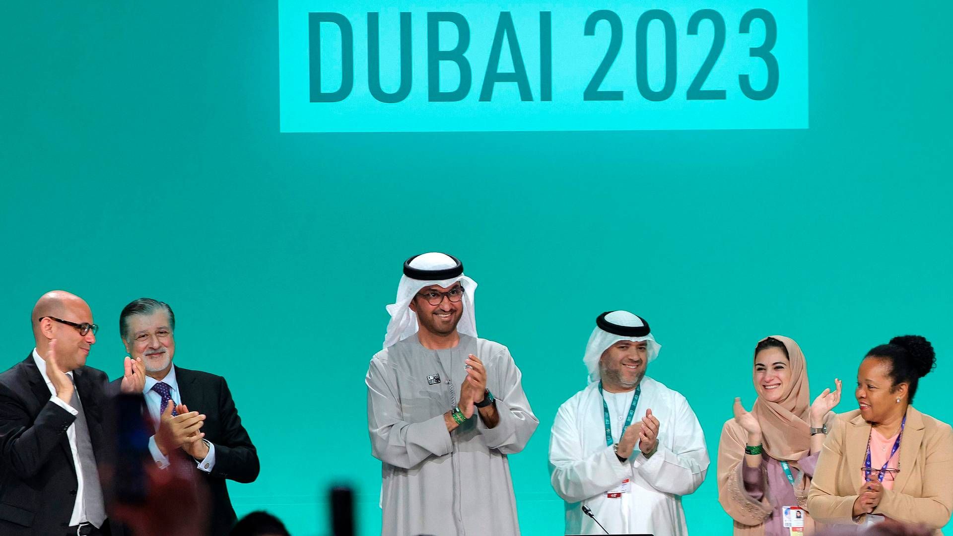 COP28 president Sultan Ahmed Al Jaber (C) applauds among other officials before a plenary session during the United Nations climate summit in Dubai on December 13, 2023. Nations adopted the first ever UN climate deal that calls for the world to transition away from fossil fuels. | Photo: Giuseppe Cacace/AFP/Ritzau Scanpix