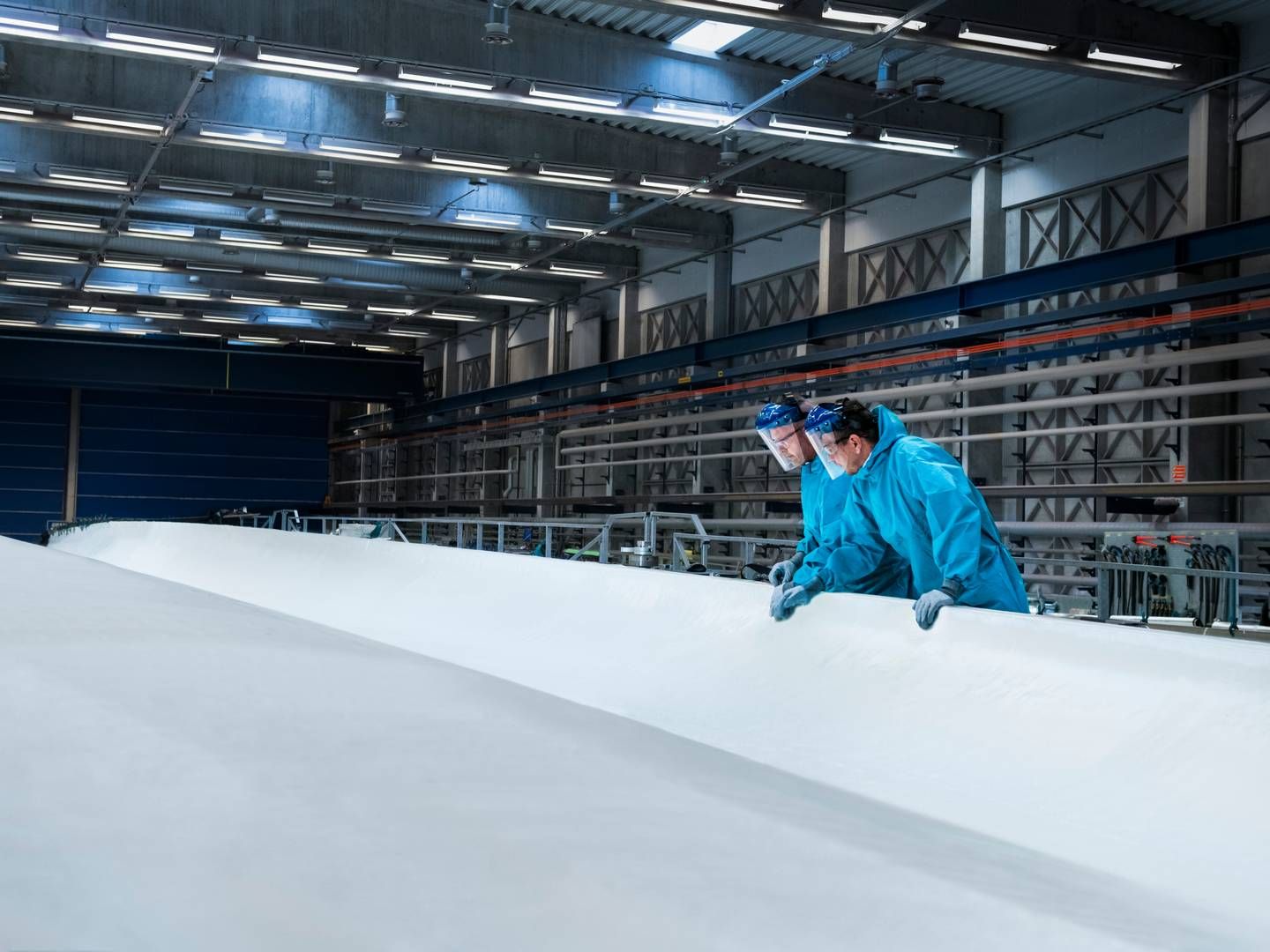 Two Vestas employees inspect the construction process of a 115.5 metre long V236-15.0MW wind turbine blade at Nakskov, Denmark. | Photo: vestas
