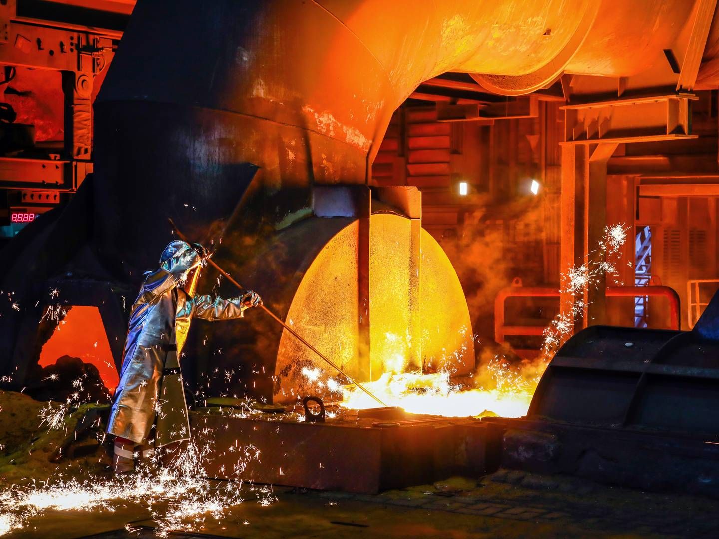 ThyssenKrupp Steel, ein Stahlarbeiter im Schutzanzug entnimmt eine 1500 Grad heiße Roheisenprobe beim Abstich am Hochofen. In der Stahlindustrie geht es um den kompletten Umbau der Produktionsverfahren, um grünen Stahl produzieren zu können. | Foto: picture alliance / Rupert Oberhäuser