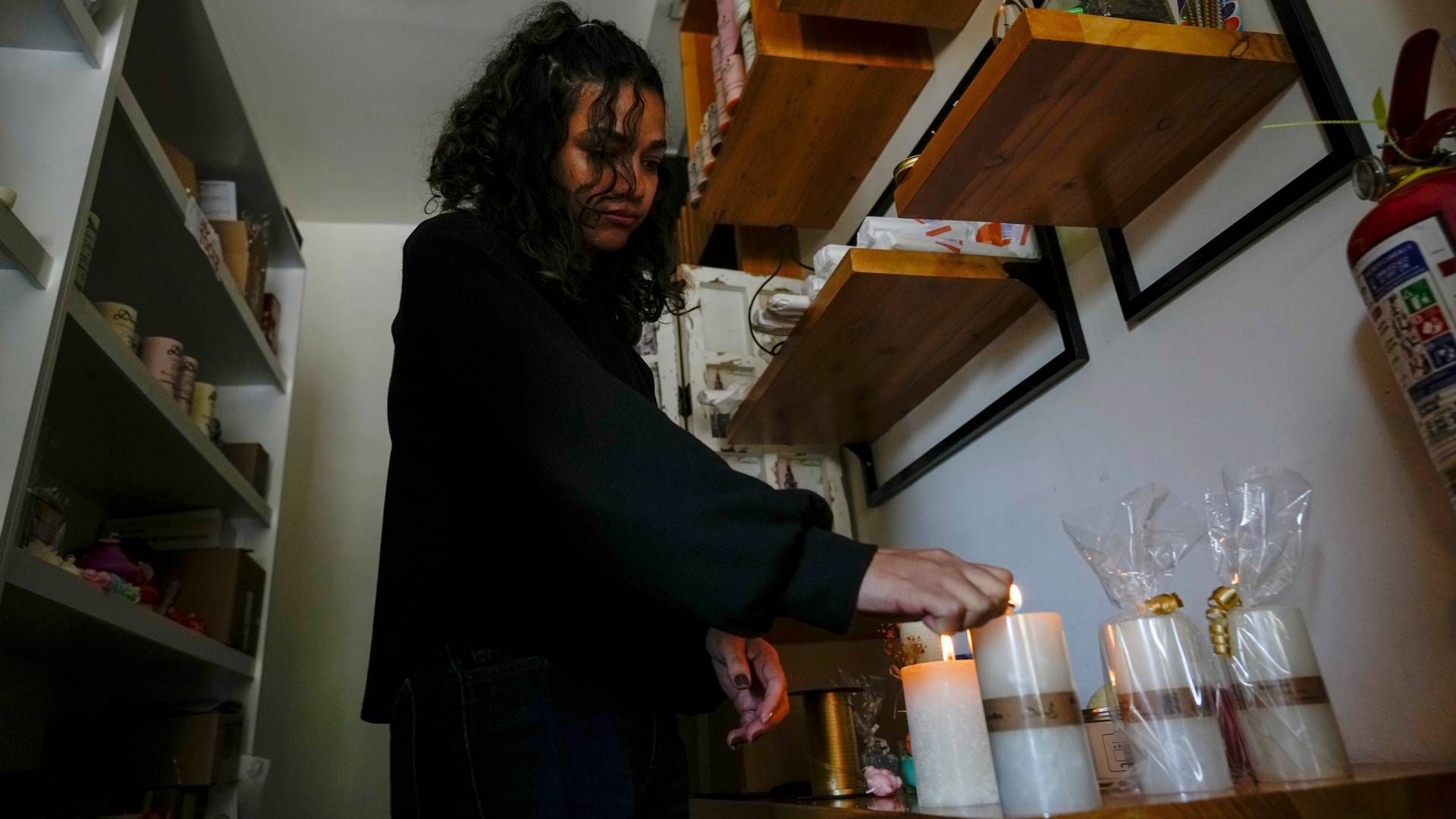 Rasjonering av strøm er realitet i Ecuador denne uken etter at myndighetene har erklært strømkrise som følge av tørke. Bildet er fra en butikk i hovedstaden Quito der en kvinne tenner stearinlys etter at strømmen er blitt kuttet. | Foto: Dolores Ochoa / AP / NTB