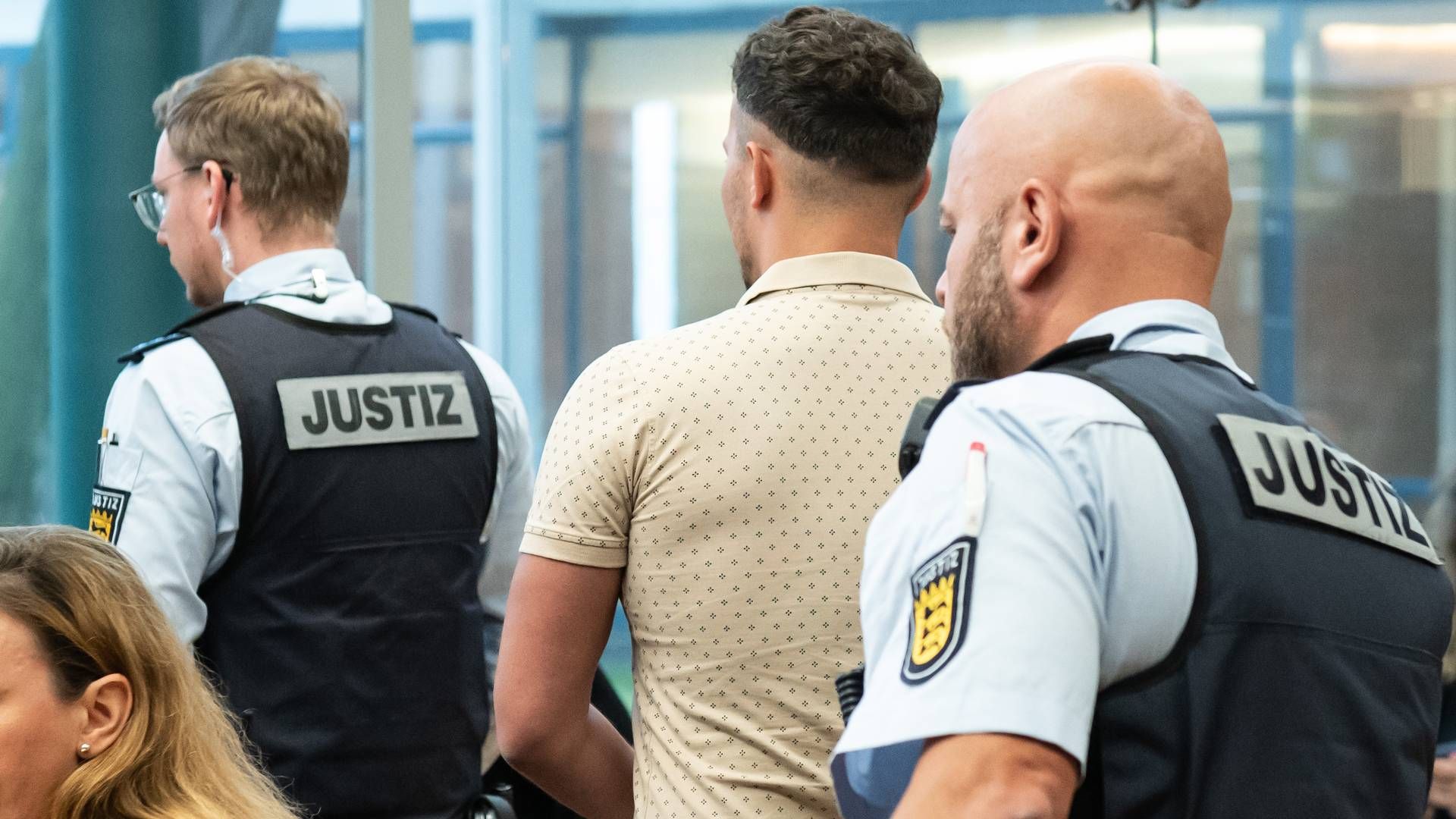 Ein des Menschenhandels Angeklagter wird vor Prozessbeginn von Justizbeamten mit Handschellen in den Gerichtssaal des Landgerichts Konstanz gebracht. | Foto: picture alliance/dpa | Silas Stein