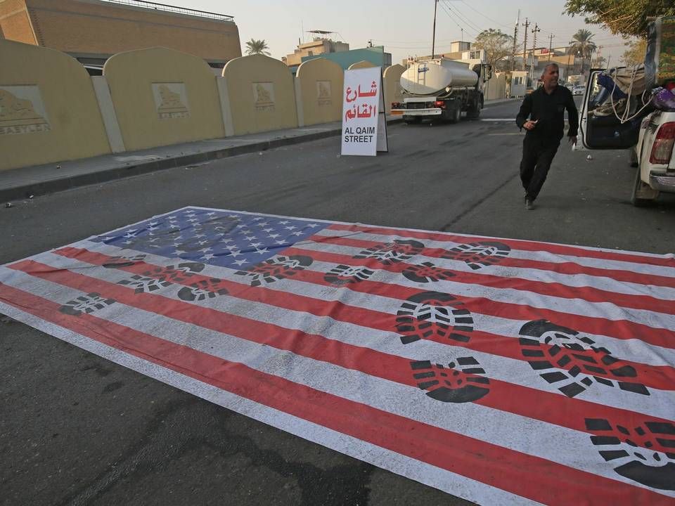 Et amerikansk flag ligger på jorden i den irakiske hovedstad Bagdad efter drabet på den iranske generalmajor Qassem Soleimani ved byens lufthavn. | Foto: AHMAD AL-RUBAYE/Ritzau Scanpix/AFP/AFP