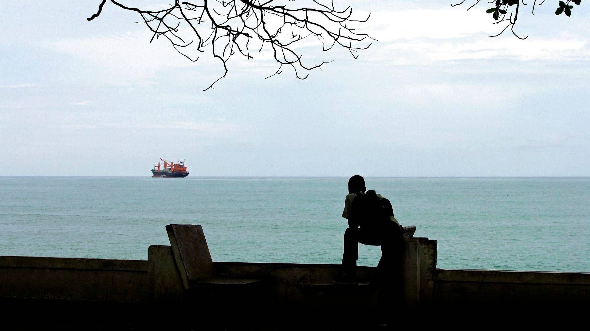 En skoledreng kigger på et handelsskib i Guineabugten i dette arkivbillede. Billedet viser ikke pirater eller det omtalte skib. | Foto: Armando Franca/AP/Ritzau Scanpix