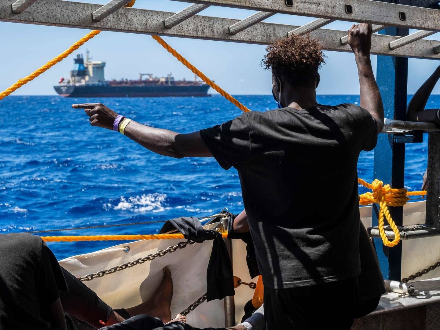Migranter ombord på et civilt skib ser over mod Maersk Etienne, der har ligget for anker ud for Maltas kyst i en måned. | Foto: THOMAS LOHNES/AFP / AFP