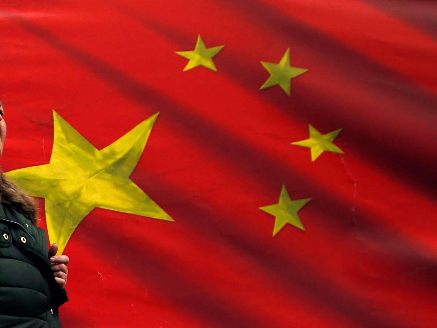 En kvinde passerer et kinesisk flagpå gaden i Beograd. Kinesiske investeringer stiger, særligt i central- og østeuropæiske lande, og EU betegner nu Kina som en "systemisk rival", men der er intet reelt overblik over de kinesiske investeringer i Europa. | Foto: Darko Vojinovic/AP/Ritzau Scanpix