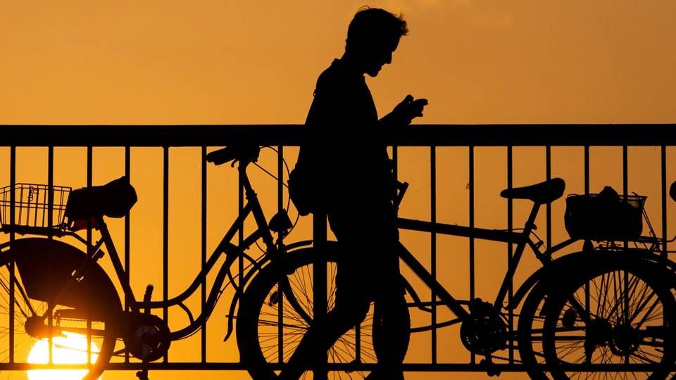 Ein junger Mann blickt auf sein Handy, während er über die Jannowitzbrücke in Berlin geht. | Foto: picture alliance/dpa