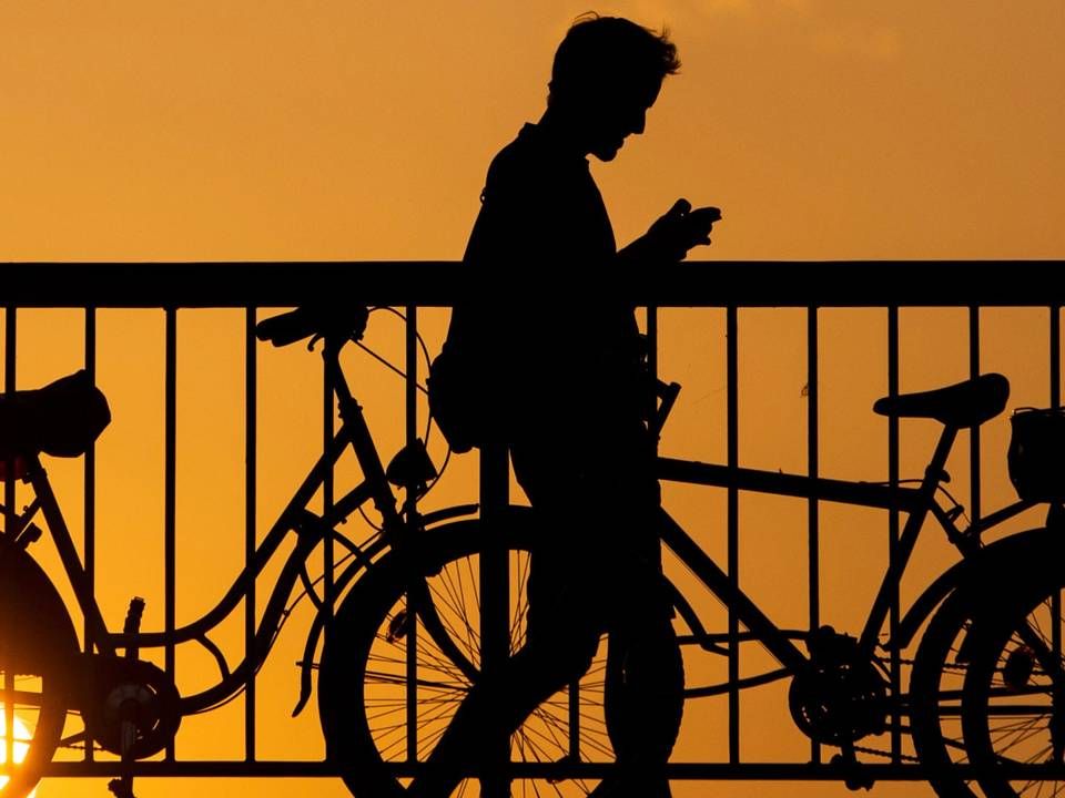 Ein junger Mann blickt auf sein Handy, während er über die Jannowitzbrücke in Berlin geht. | Foto: picture alliance/dpa