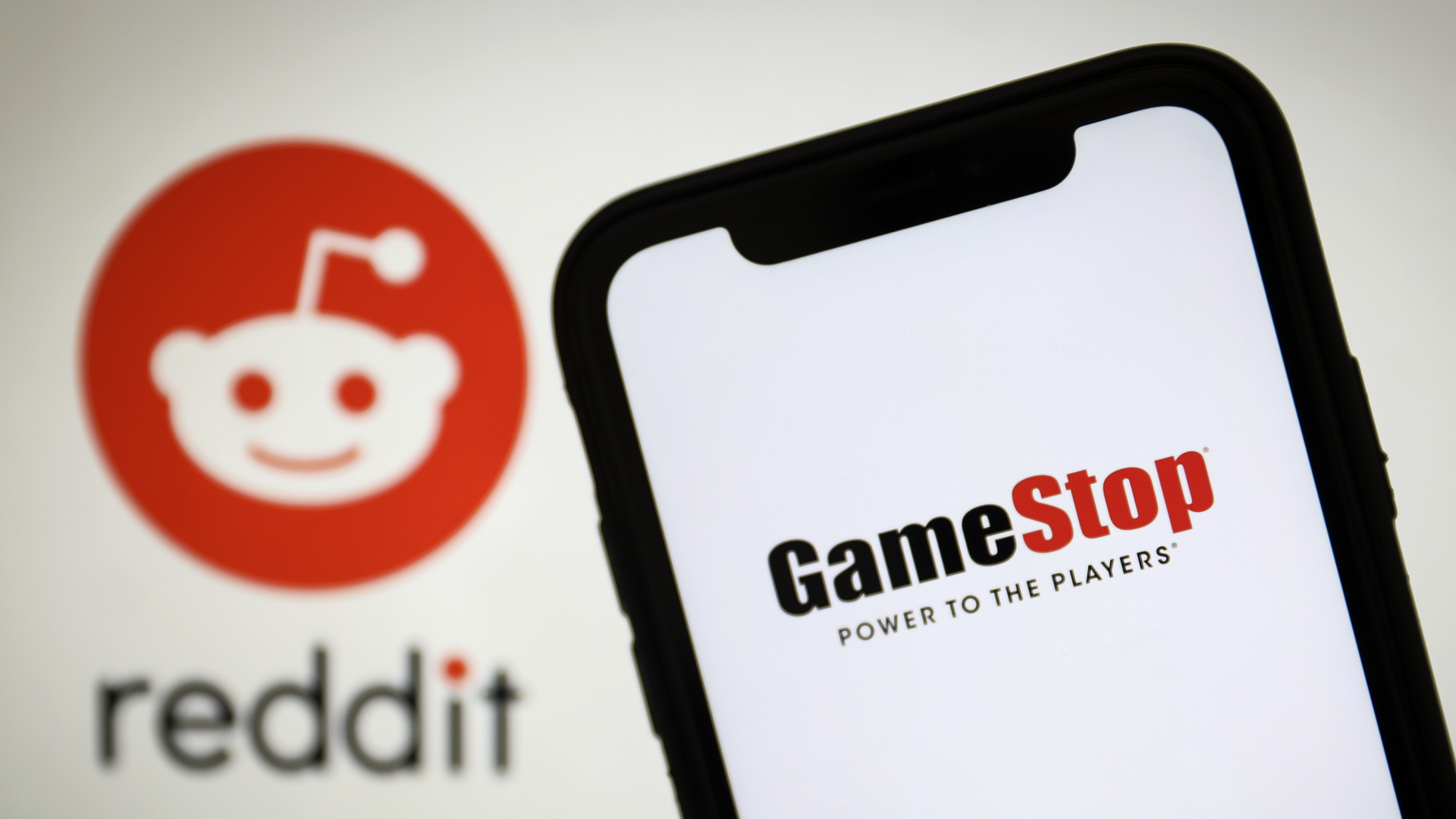 Smartphone mit dem "Gamestop"-Logo vor dem Hintergrund des "Reddit"-Logos | Foto: picture alliance / AA | Hakan Nural