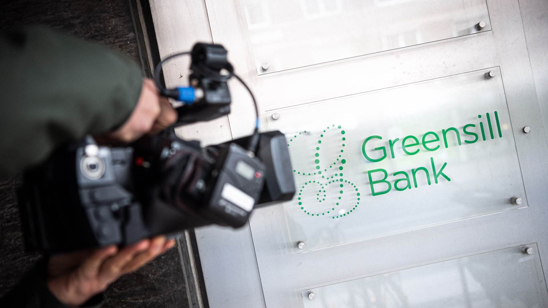 Ein Schild mit dem Firmennamen "Greensill Bank" wird von einem Fernsehteam gefilmt. | Foto: picture alliance/dpa | Sina Schuldt