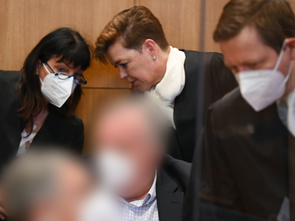 Zwei angeklagte frühere Mitarbeiter der inzwischen insolventen Maple Bank unterhalten sich vor dem Frankfurter Landgericht mit ihren Anwälten. | Foto: picture alliance/dpa/dpa/POOL