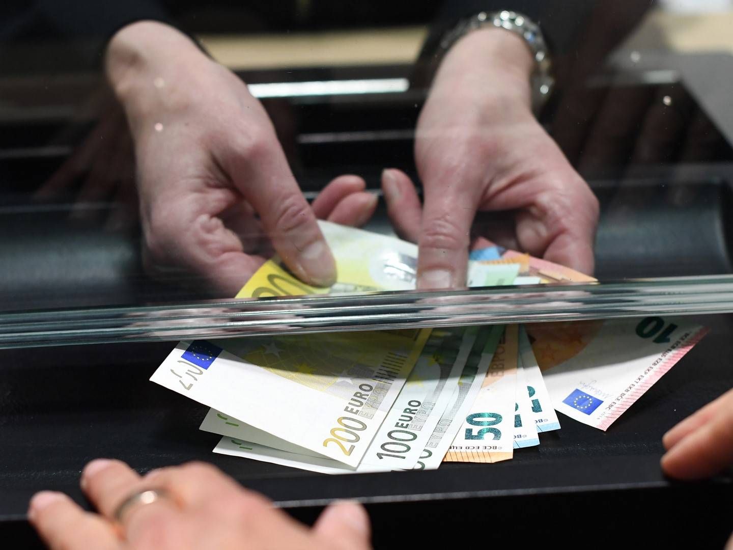 Eine Frau lässt sich in einer Bankfiliale am Schalter Bargeld auszahlen. | Foto: picture alliance/dpa | Angelika Warmuth