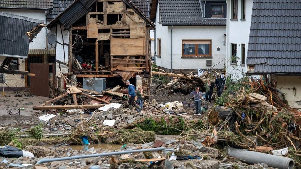 Anwohner gehen in dem Ort im Kreis Ahrweiler nach dem Unwetter mit Hochwasser durch den Schutt an einem beschädigten Gebäude vorbei. | Foto: picture alliance/dpa | Harald Tittel
