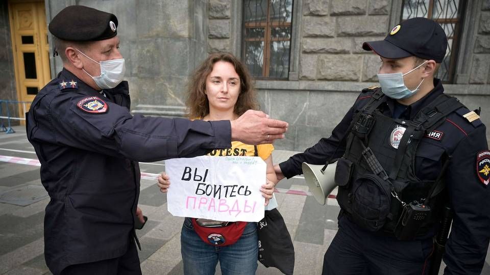Politibetjente anholder en journalist under en demonstration i Moskva lørdag. På journalistens skilt står der: "I er bange for sandheden". | Foto: Natalia Kolesnikova/Ritzau Scanpix