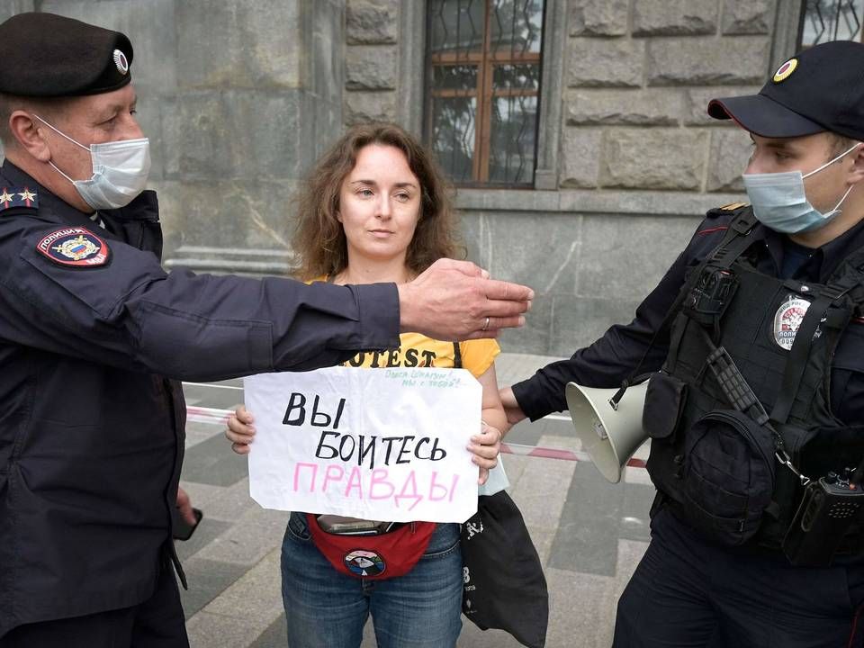 Politibetjente anholder en journalist under en demonstration i Moskva lørdag. På journalistens skilt står der: "I er bange for sandheden". | Foto: Natalia Kolesnikova/Ritzau Scanpix