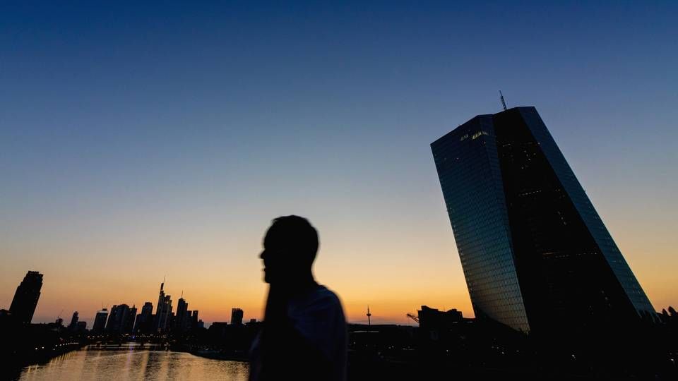 Silhouette eines Menschen, der im letzten Gegenlicht der untergegangenen Sonne an der Europäischen Zentralbank (EZB) und der Frankfurter Skyline vorbei geht. | Foto: picture alliance / greatif | Florian Gaul