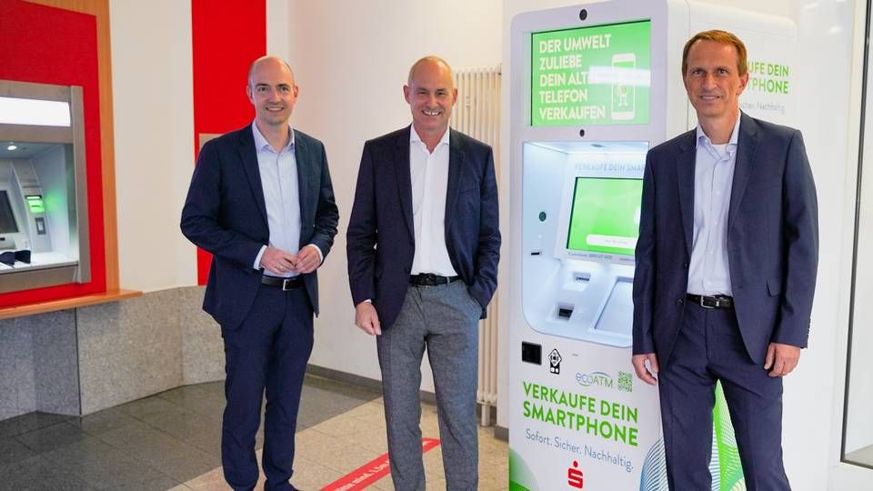 Stefan Kleiber (m.) vor dem Smartphone-Recycling-Automaten, mit seinem Vorstandskollegen Marcel Becker (l.) und Jörg Schäfer von EcoATM. | Foto: Sparkasse Rhein Neckar Nord
