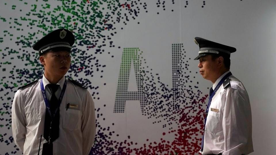 Vagter foran et AI-skilt ved en Huawei konference.
