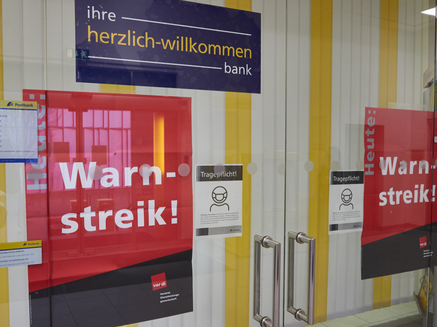 Schilder mit der Aufschrift „"Warnstreik"“ kleben an den geschlossenen Glastüren einer Postbankfiliale. | Foto: picture alliance/dpa | Georg Wendt
