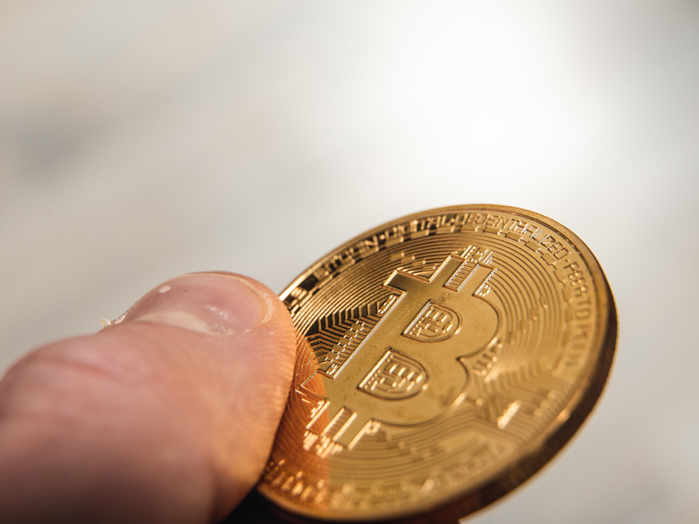Ein Mann hält eine Bitcoin Gold Münze in der Hand, digitale Krypto Währung | Foto: picture alliance / CHROMORANGE | Michael Bihlmayer