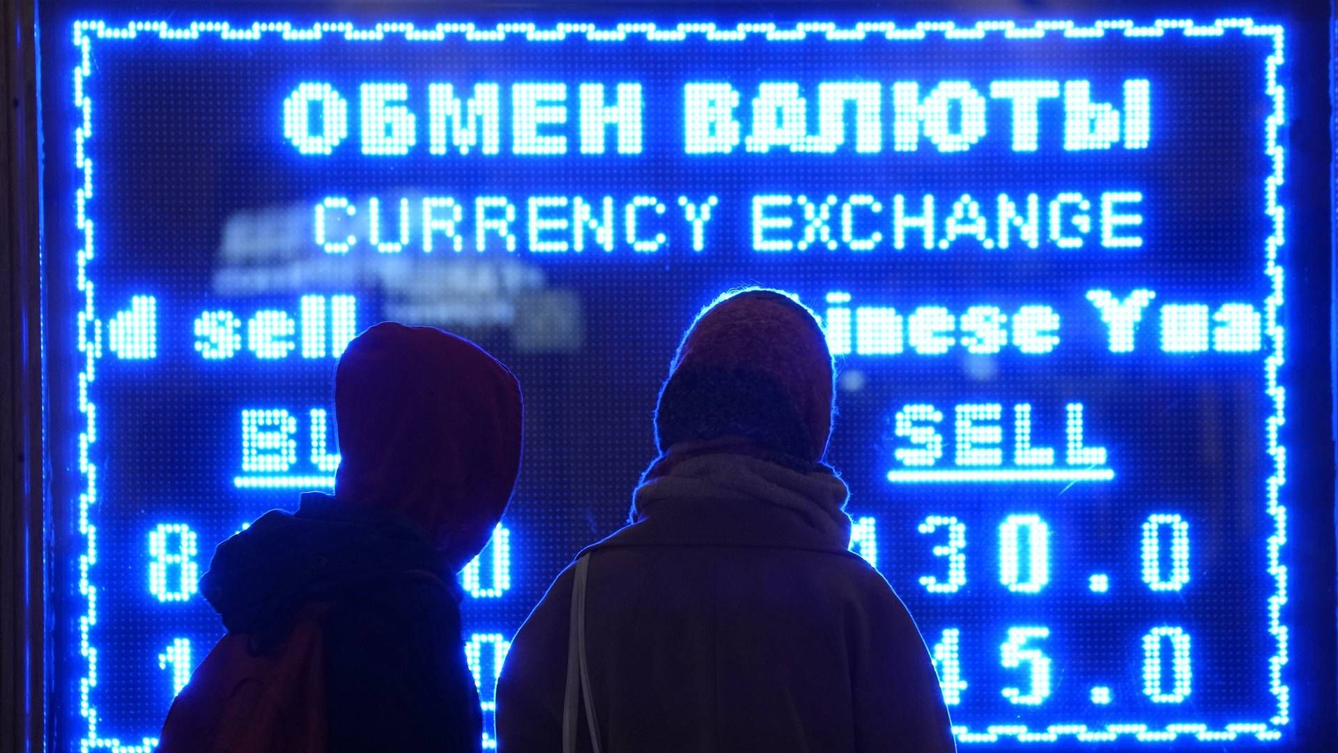 To personer ser på en skjerm som viser valutakurs på et valutavekslingskontor i St. Petersburg i Russland, tirsdag 1. mars 2022. | Foto: Dmitri Lovetsky / AP