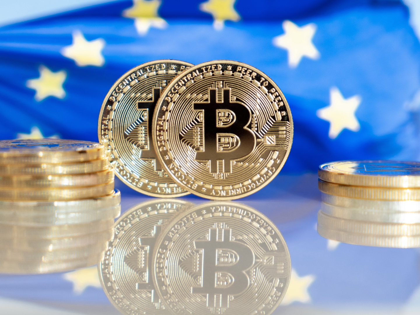 Fiktive Münzen der Kryptowährung Bitcoin vor Europaflagge. | Foto: picture alliance / Daniel Kalker