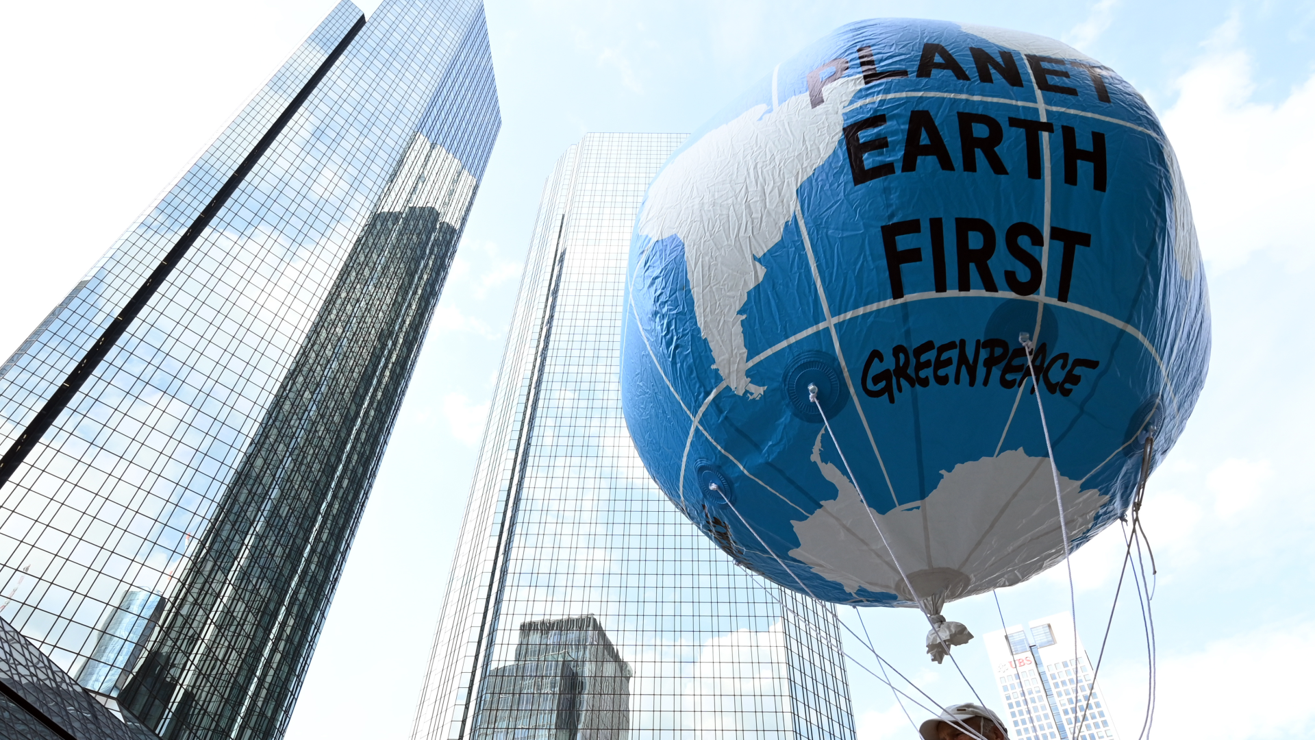 Vor der Zentrale der Deutschen Bank in Frankfurt hält ein Demonstrant einen großen Ballon mit dem Schriftzug "Planet Earth First" beim zentralen Klimastreik von Fridays for Future im Sommer 2021 hoch. | Foto: picture alliance/dpa | Arne Dedert