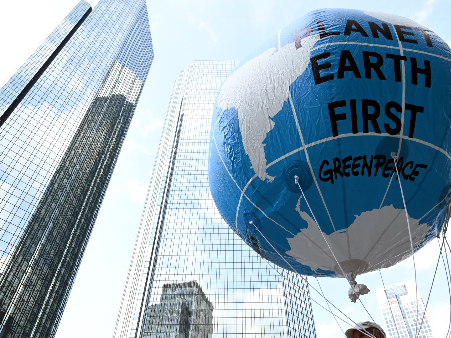Vor der Zentrale der Deutschen Bank in Frankfurt hält ein Demonstrant einen großen Ballon mit dem Schriftzug "Planet Earth First" beim zentralen Klimastreik von Fridays for Future im Sommer 2021 hoch. | Foto: picture alliance/dpa | Arne Dedert