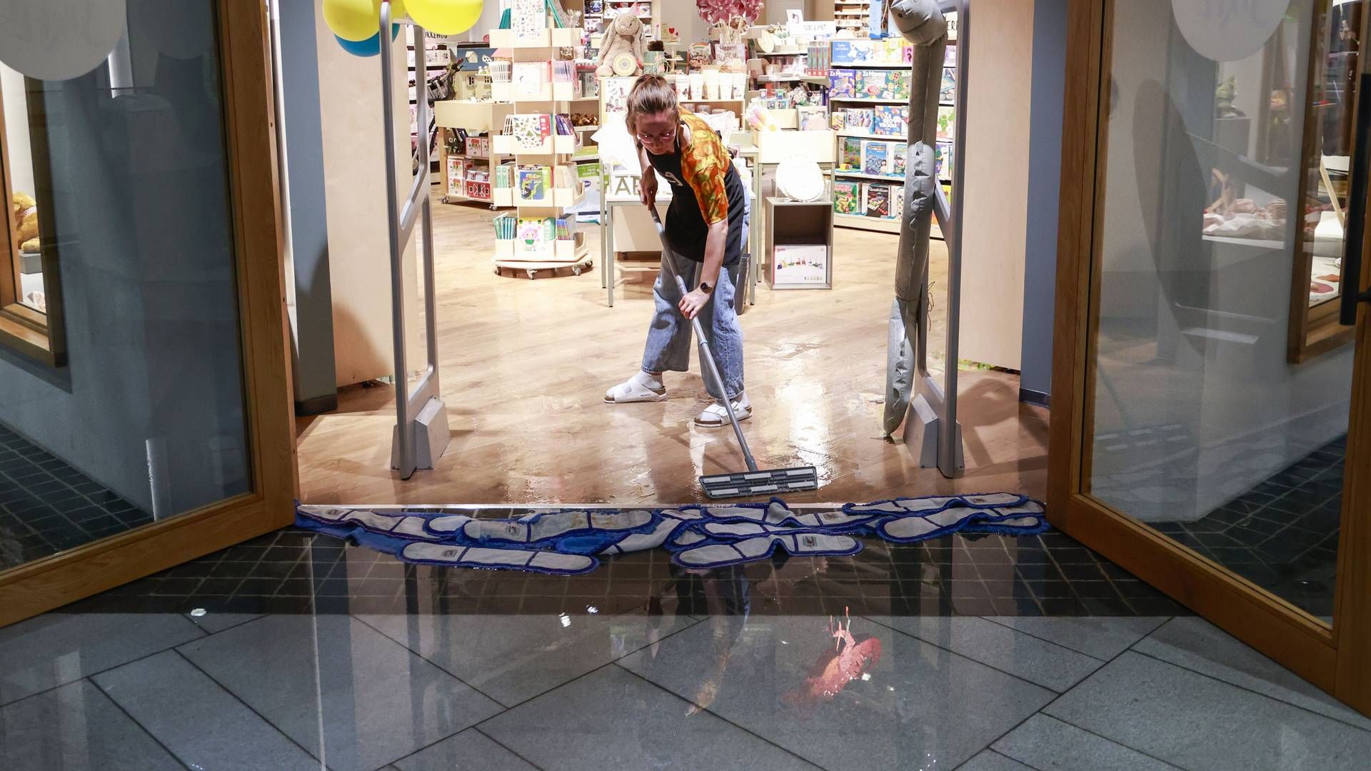 De ansatte i Torgkvartalet kjøpesenter tørker opp vann fra gulvet, etter at kraftig regnvær førte til oversvømmelser flere steder i Kristiansand fredag ettermiddag. | Foto: Tor Erik Schrøder / NTB