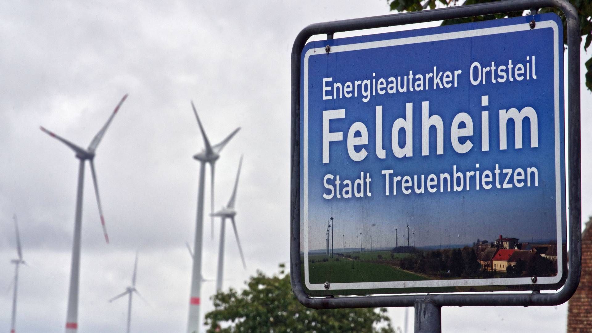 SELVFORSYNT BYGD: Vindturbiner i bygda Feldheim i Tyskland. På skiltet står det "Det energimessig selvforsynte distriktet Feldheim". | Foto: AP Photo/Michael Soh