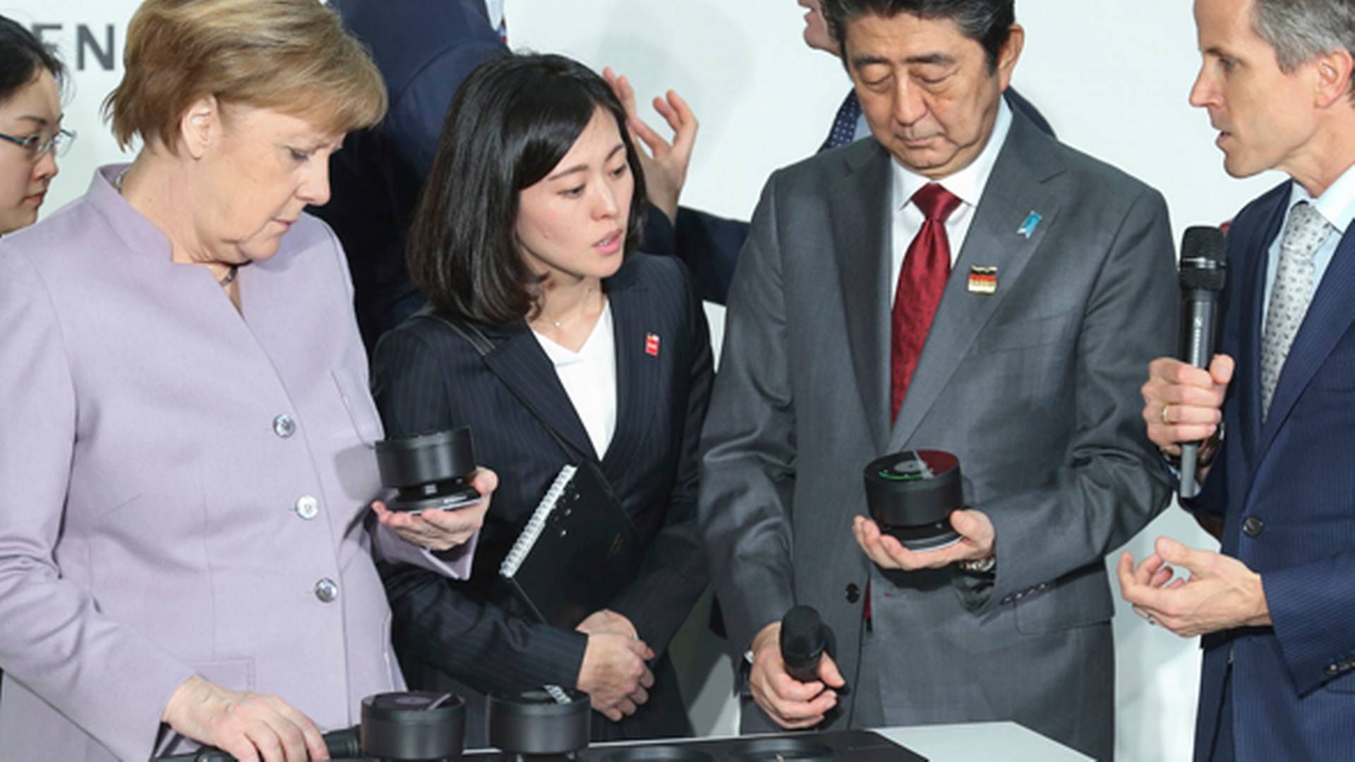 Den tyske kansler Angela Merkel inspicerer Sennheisers produkter på Cebit-messen sammen med den japanske ministerpræsident Shinzo Abe og Andreas Sennheiser ydest til højre.